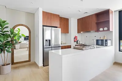a kitchen with a white counter top and wooden cabinets at Ocean View 2BR with a Pool & Gym, 2 min to Beach in Dubai