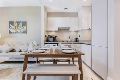 a kitchen and living room with a wooden table and chairs at STAY BY LATINEM Luxury 1BR Holiday Home CVR A2003 near Burj Khalifa in Dubai