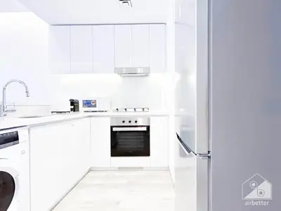 a white kitchen with a stove and a refrigerator at Modern 1-Bedroom Haven in Ahad Residence in Dubai