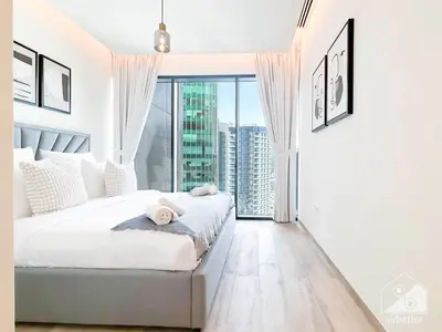 a white bedroom with a bed and a large window at Modern 1-Bedroom Haven in Ahad Residence in Dubai