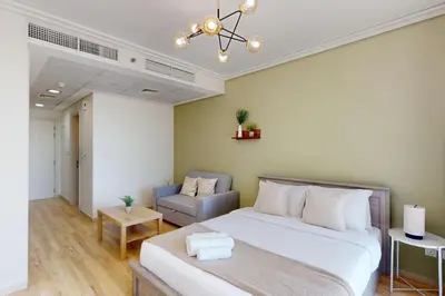 a bedroom with a large white bed and a chair at Goldcrest Views 2 - Elegant Studio in Dubai