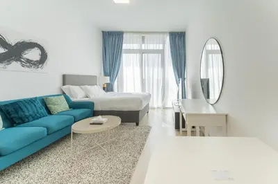 a living room with a blue couch and a bed at HAVN - Studio Apartment in Bloom Towers, JVC in Dubai