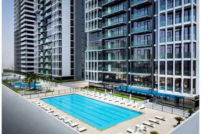 an apartment complex with a pool and chairs and buildings at HAVN - Studio Apartment in Bloom Towers, JVC in Dubai