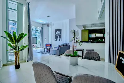 a dining room and living room with a table and chairs at New Modern Apartment 1BHK 5 min walk to Dubai Mall 99walk score in Dubai