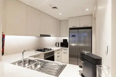 a kitchen with white cabinets and a stainless steel refrigerator at Stunning Burj & Fountain Views Luxury 2 BR in Dubai