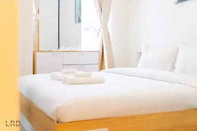 two beds in a bedroom with white sheets and towels at New Cozy 1BR Dubai Hills in Dubai