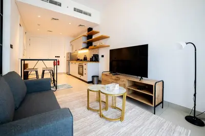 a living room with a couch and a tv and a table at New Cozy 1BR Dubai Hills in Dubai