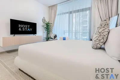 a white bed in a room with a tv at Boutique Studio in Wilton Park MBR City in Dubai