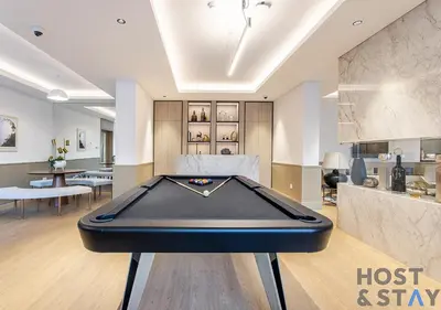 a living room with a pool table in the middle at 1BR Belgravia Apartment with pool view in Dubai