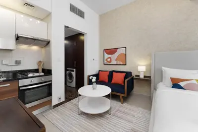 a room with a bed and a table and a kitchen at Elegant studio in Sparkle Tower by Suiteable in Dubai