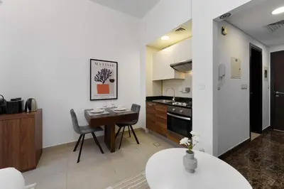 a kitchen with a table and a dining room at Elegant studio in Sparkle Tower by Suiteable in Dubai