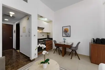 a kitchen and living room with a table and chairs at Your gateway in Sparkle Tower JBR by Suiteable in Dubai