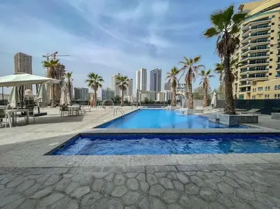 a large swimming pool with palm trees and buildings at Your gateway in Sparkle Tower JBR by Suiteable in Dubai