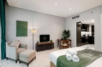 a bedroom with a bed and a chair and a television at DAMAC APARTMENTS in Dubai