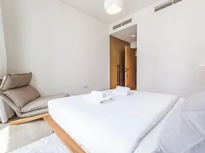 a white bedroom with a bed and a couch at The Harbor Heights 1BR in Palace Residences Creek in Dubai