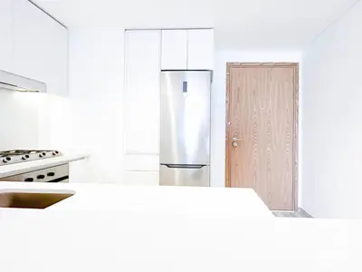 a white kitchen with a refrigerator and a door at Stylish 1Bedroom with Balcony & View Dubai in Dubai