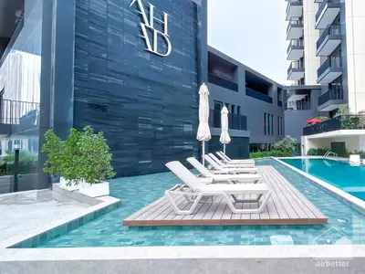 a group of chairs and umbrellas next to a pool at Stylish 1Bedroom with Balcony & View Dubai in Dubai
