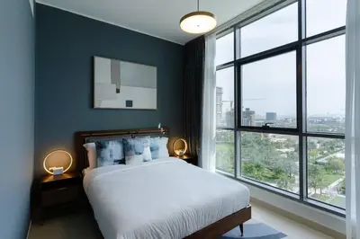 a bedroom with a bed with blue walls and windows at Stylish and Cozy l Park View l Next to Mall in Dubai