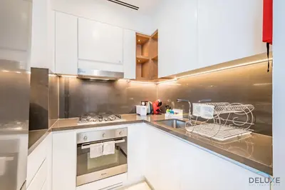 a kitchen with white cabinets and a stove at Chic 1BR in VIDA Residences Dubai Marina by Deluxe Holiday Homes in Dubai