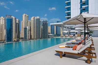 a pool with lounge chairs and an umbrella on a building at Chic 1BR in VIDA Residences Dubai Marina by Deluxe Holiday Homes in Dubai