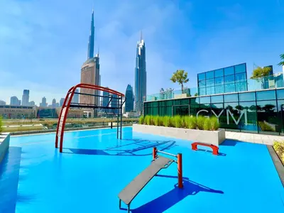 a swimming pool with a slide in front of a city skyline at Downtown Views 2BR - Dubai Mall, Fountain & Burj Khalifa access in Dubai