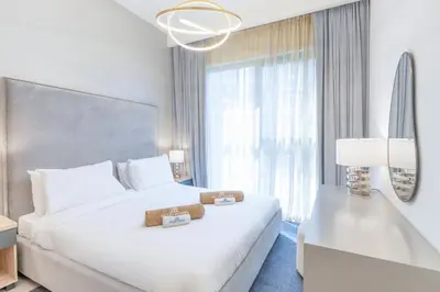 a bedroom with a white bed and a large window at Branded 2BR Residence with Direct Park Access in Dubai