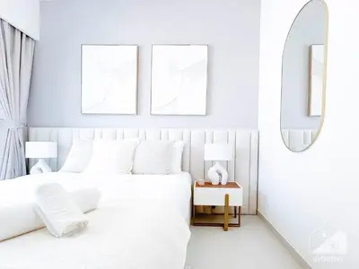 a white bedroom with a white bed and two frames at Luxurious Living in 2B with Burj & Fountain Views in Dubai