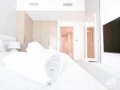 a white bedroom with a white bed and a flat screen tv at Luxurious Living in 2B with Burj & Fountain Views in Dubai