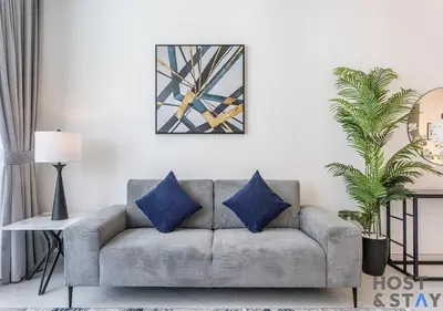 a living room with a gray couch with blue pillows at 1 Bedroom - Crystal Lagoon - MBR City Meydan in Dubai