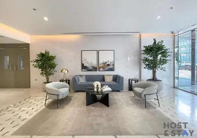 a living room with a blue couch and two chairs at 1 Bedroom - Crystal Lagoon - MBR City Meydan in Dubai