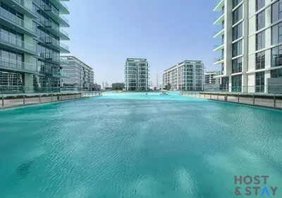 a large swimming pool in a city with tall buildings at 1 Bedroom - Crystal Lagoon - MBR City Meydan in Dubai