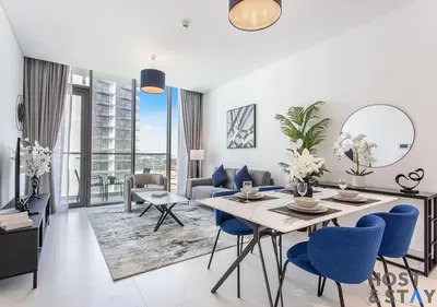 a living room with a table and blue chairs at 1 Bedroom - Crystal Lagoon - MBR City Meydan in Dubai