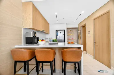 a kitchen with a counter and two chairs at a counter top at Breathtaking 1BR in Palm Tower, with Sea View in Dubai