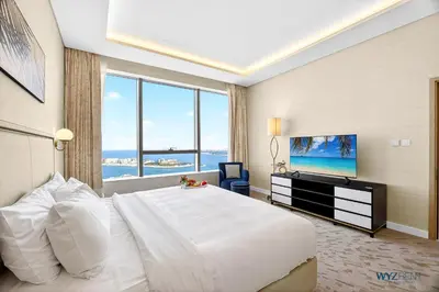 a bedroom with a large white bed and a television at Breathtaking 1BR in Palm Tower, with Sea View in Dubai