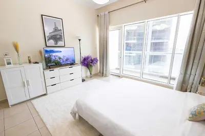 a white bedroom with a bed and a tv at Dubai Downtown Dubai Mall & Burj Khalifa DIFC 5 mins in Dubai