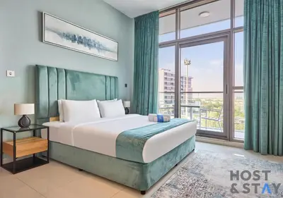 a bedroom with a bed and a large window at Serene 1 BR in Damac Hills - Host & Stay in Dubai