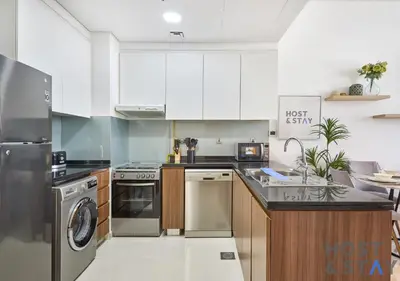 a kitchen with white cabinets and stainless steel appliances at Serene 1 BR in Damac Hills - Host & Stay in Dubai