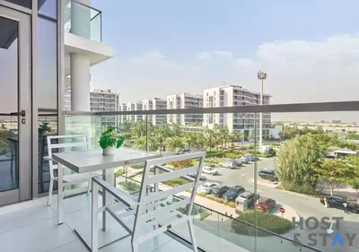 a balcony with a table and chairs and a view of a city at Serene 1 BR in Damac Hills - Host & Stay in Dubai