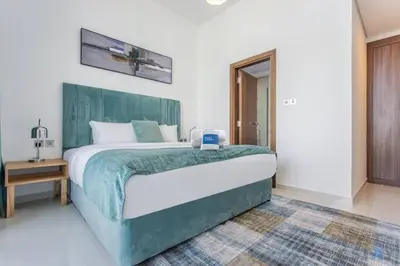 a bedroom with a large bed with a laptop on it at Lively 1 BR in Damac Hills, Dubai - Host & Stay in Dubai