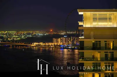 a view of a city at night with the london eye at LUX The Marina Vista Beachfront Suite 2 in Dubai