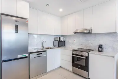 a kitchen with white cabinets and a stainless steel refrigerator at One Bedroom Apartment in Madinat Jumeirah Living by The S Holiday Homes in Dubai