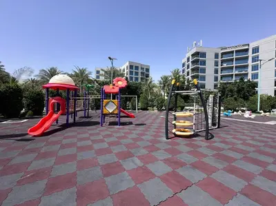 a playground in a parking lot with slides and swings at Mag 510: 2-Bedroom Elegance in Dubai
