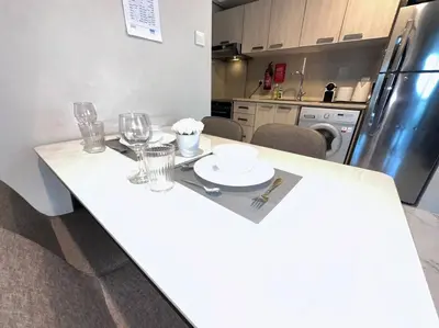 a kitchen with a white table with glasses and a plate at Mag 510: 2-Bedroom Elegance in Dubai