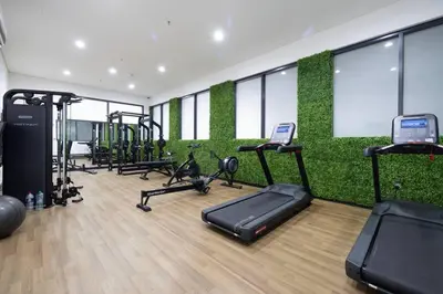 a gym with a green wall with tread machines at Large 1BR in JVC Sleeps 4 Rooftop, Pool & Gym in Dubai