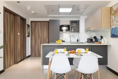 a kitchen with a white table and white chairs at Large 1BR in JVC Sleeps 4 Rooftop, Pool & Gym in Dubai