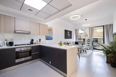 a kitchen with a counter and a living room at Large 1BR in JVC Sleeps 4 Rooftop, Pool & Gym in Dubai