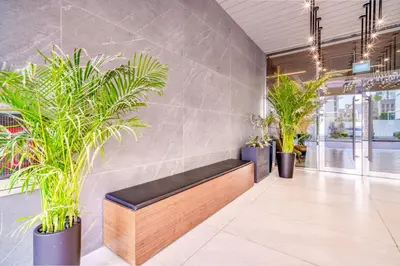 a bench in a lobby with potted plants at Stella Stays Lana Tower in Dubai