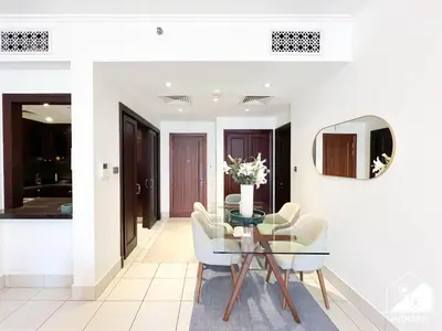a dining room with a glass table and white chairs at Luxury 2Bedroom with Terrace & Burj Khalifa view in Dubai