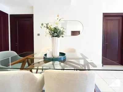 a glass table with a vase of flowers on it at Luxury 2Bedroom with Terrace & Burj Khalifa view in Dubai
