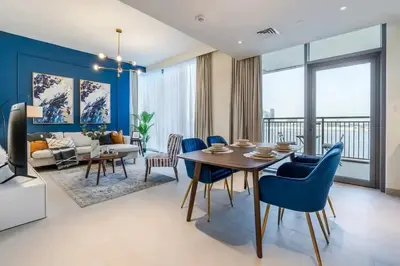 a living room with a dining room table and blue chairs at Guest Favourite! Beautiful 1 bedroom apartment in Dubai